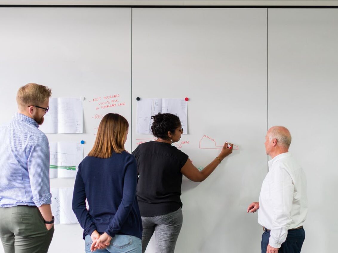 A team working through a problem at a whiteboard